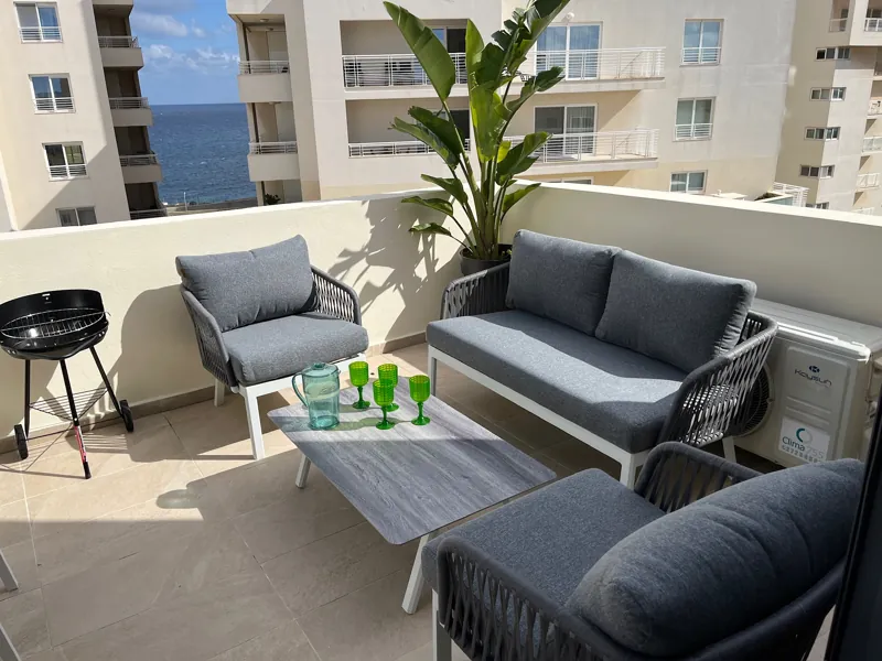 Front terrace lounge with grey outdoor sofas, a barbecue and a view of the sea